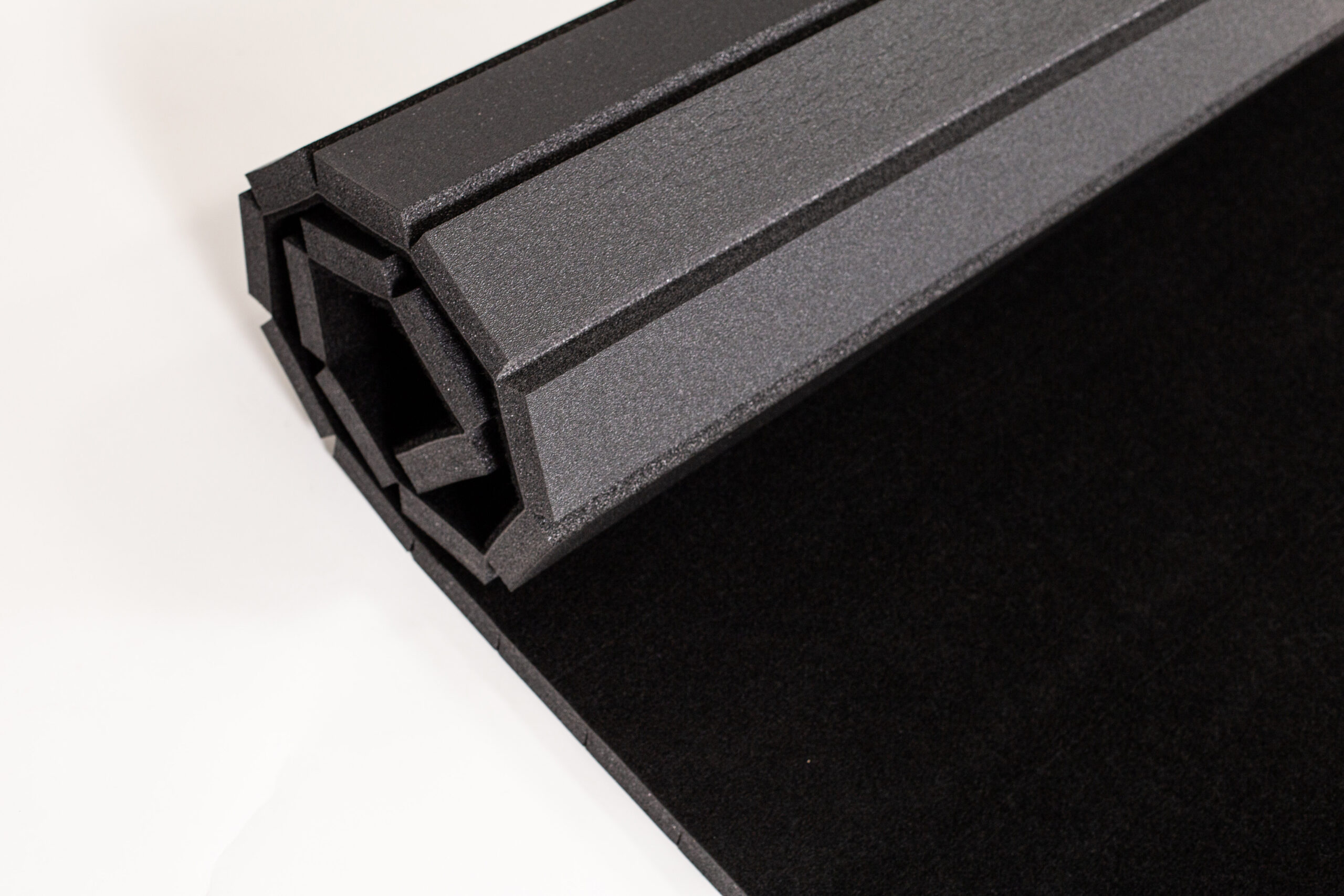 Rolled black carpet bonded foam flooring with a cushioned foam backing.