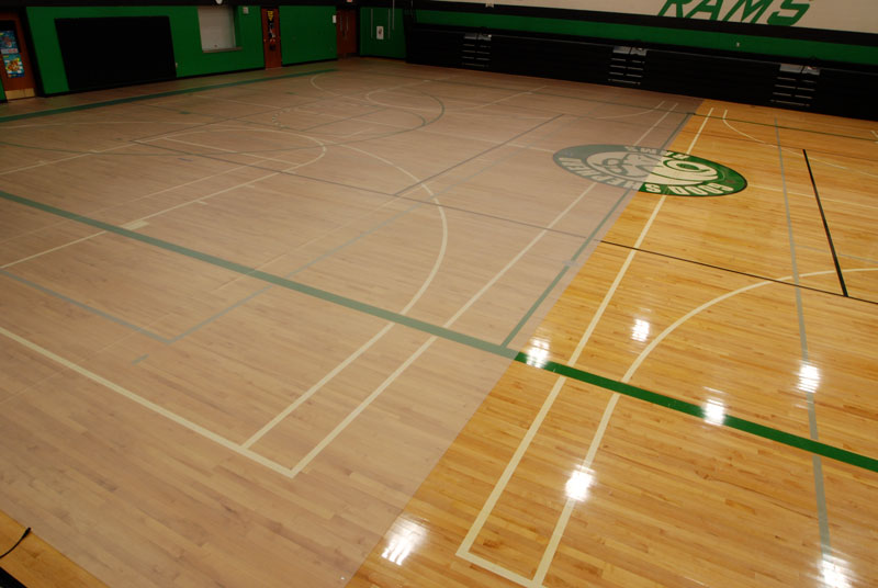 Clear protective gym floor covering installed over part of a school basketball court