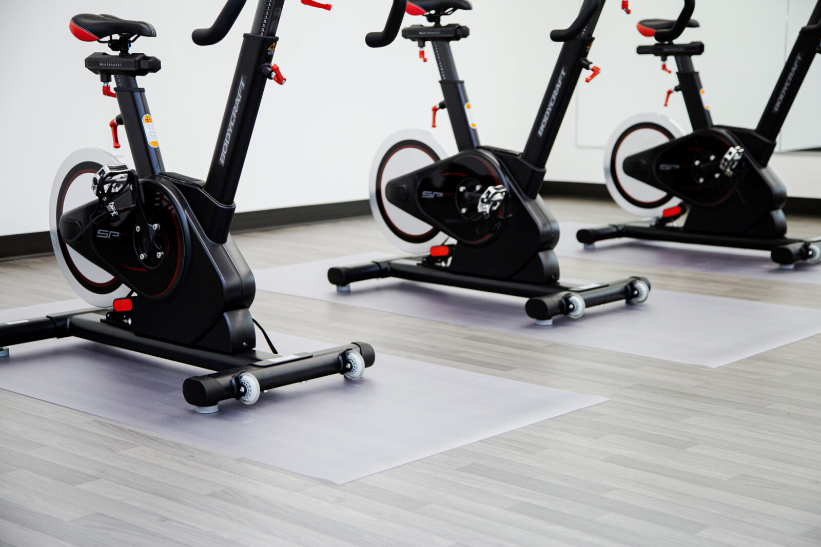 three exercise bikes on clear floor protector mats